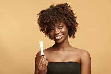 African American woman smiles, keeps small white tube mockup.