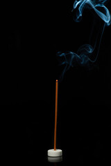 Incense on a black background with blue smoke.