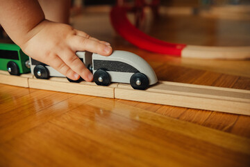 little child playing with wooden railroad. toy train rides on rails.