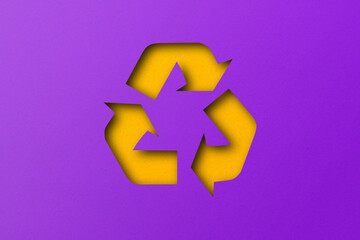 Yellow paper punched cut into recycled shapes isolated on purple paper background.