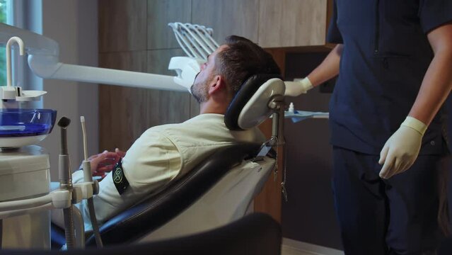 Man dentist preparing patient for the procedure in light dental clinic. Hydience and healthy