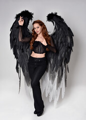Full length portrait of beautiful woman with long red hair wearing sheer corset top, leather pants,...