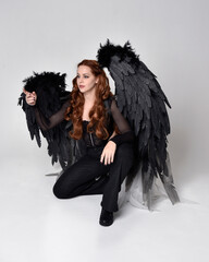 Full length portrait of beautiful woman with long red hair wearing sheer corset top, leather pants...
