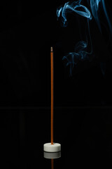 Incense on a black background with blue smoke.