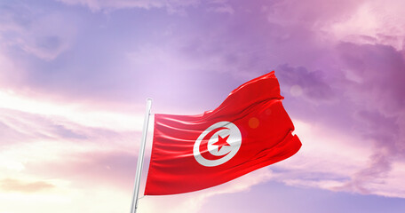 Waving Flag of Tunisia in Blue Sky. The symbol of the state on wavy cotton fabric.