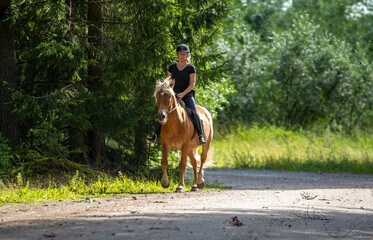 Woman horseback riding in forest trail
