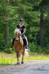 Woman horseback riding in forest trail