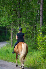 Woman horseback riding in forest trail
