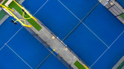 Perpendicular aerial view on padel courts. Characteristic blue flooring and glass that serve as walls. Closeup. Sports concept.