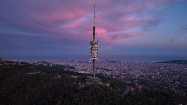 Torre de Collserola communications tower at sunset on Tibidabo with Barcelona city in background, Spain. Aerial drone view and cloudscape