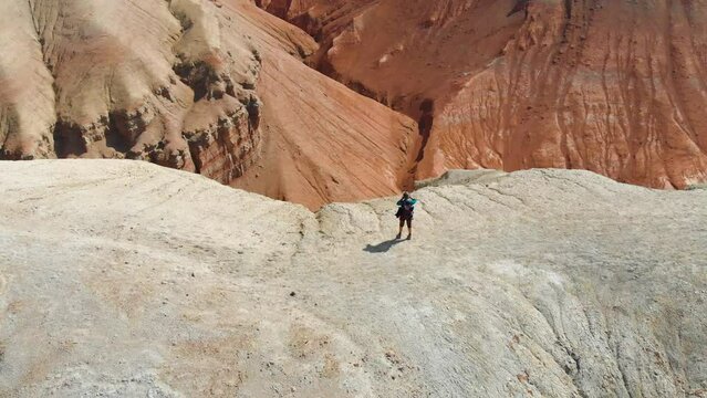A man shoots a photo standing on top of a hill among the desert mountains. Desert terrain. Aerial video shooting
