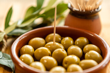 Close-up of a clay jar with olives and a toothpick stuck in it with the background out of focus. Typical Spanish food. With copy space