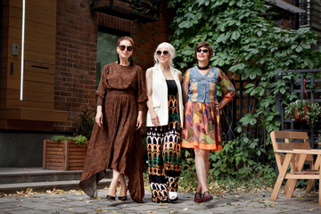 Beautiful middle aged women walking city street. Elderly fashion models wearing stylish clothes....
