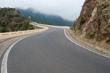 Sharp bends of winding mountain road and white clouds ahead. Rural Park Anaga in cloudy weather, Tenerife, Canary Islands, Spain