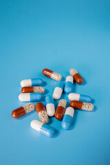 Many pills capsules on a blue background. Disease treatment concept