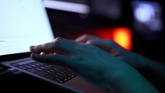 Close up of Unrecognizable Caucasian man hands typing on a laptop, dark background. Copy space.