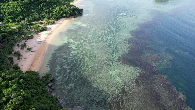 Stunning Aerial view of Coastal Reef under clear Oceans Waves next to white sand beach in Catanduanes, Philippines.
