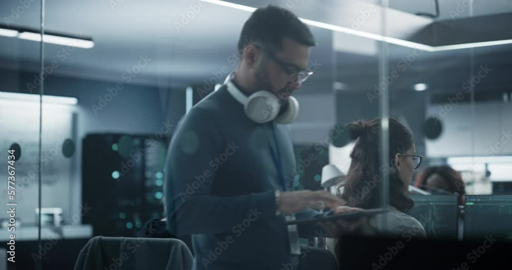 Poster Industrial Software Development Department Manager Walking and Using a Tablet Computer. Multiethnic Man Hesitates for a Second and Stops to Think and Look Around the Office