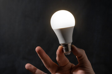Close-up of man hand holding energy saving LED lamp. Saving energy and energy crisis concept....