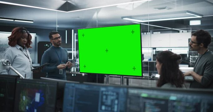 Group of Multiethnic Software Developers Having a Meeting in a Conference Room with Green Screen Mock Up Display. Specialists Brainstorming New Ideas and Solving Problems in the Office