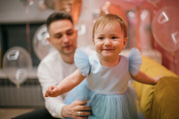 Family portrait. A little girl in a princess dress with a young dad is happy on her first birthday.