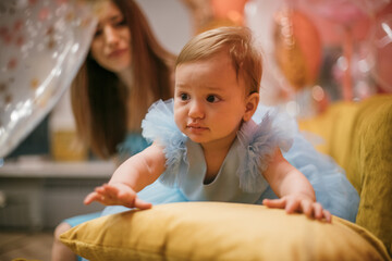 Family portrait. A little one-year-old girl in a princess dress with a young mother is happy and smiling.