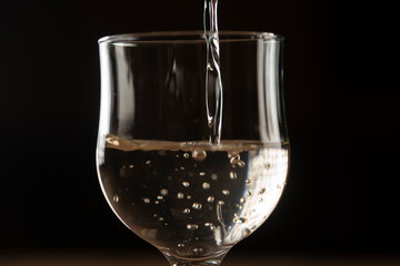 girl hands pouring red wine into a glass from a clay bottle on a black background