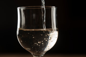 girl hands pouring red wine into a glass from a clay bottle on a black background