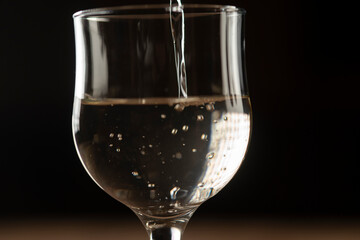 girl hands pouring red wine into a glass from a clay bottle on a black background