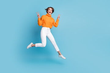 Fototapeta na wymiar Full length photo of lovely young lady jumping show double v-sign active wear trendy orange outfit isolated on blue color background