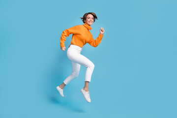 Fototapeta na wymiar Full body photo of attractive young woman running energetic cheerful active wear trendy orange outfit isolated on blue color background