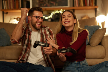 Young couple having fun at home playing video games