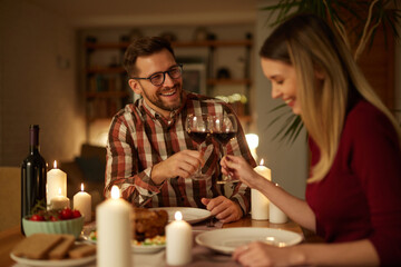 Beautiful couple having romantic dinner with candles and red wine at home