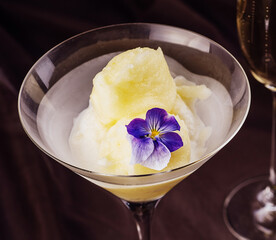 Peach and melon sorbet in bowl with a glass of champagne