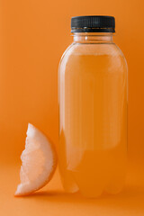 Bottle of fresh orange juice on yellow background