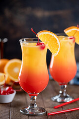 Tequila sunrise cocktail garnished with cherry and orange slice - 577378069
