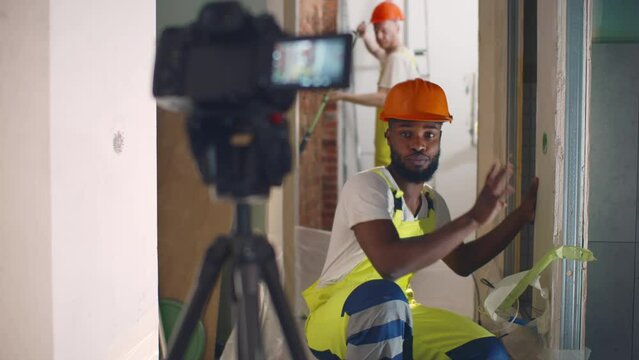 Man recording video on camera at new home during repair and installation of walls. Realtime