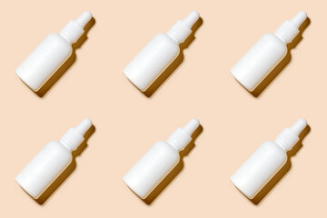 Pattern of anti aging serum in white bottle with dropper on pastel beigh background. Cosmetic pattern, flat lay