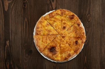 Baked homemade meat pie on wooden background.