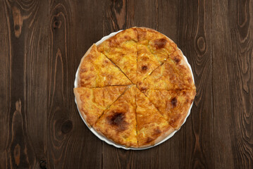 Baked homemade meat pie on wooden background.