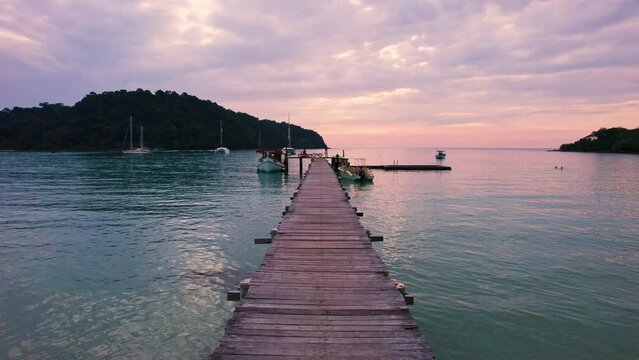 Beautiful sunset over tropical sea and wooden pier, sightseeing boat and tourist enjoying in Koh Kood Island