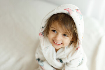 A newly washed charming baby in a bathrobe. Family morning at home. A smiling child looking at the camera. The concept of healthy hygiene for children.