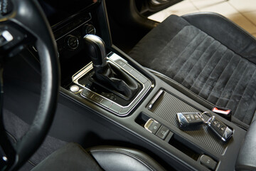 car keys are on the center console. glove box closed with a curtain. handbrake button, shift lever...