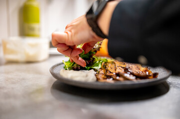 professional chef's hands cooking sliced meat beef brisket with salad and toast in restaurant kitchen