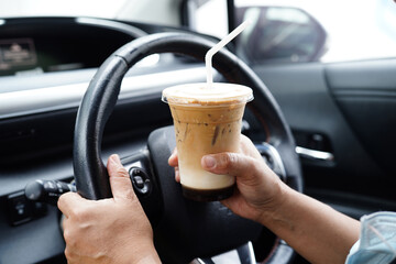 Asian woman driver hold ice coffee cup for drink in car, dangerous and risk an accident..
