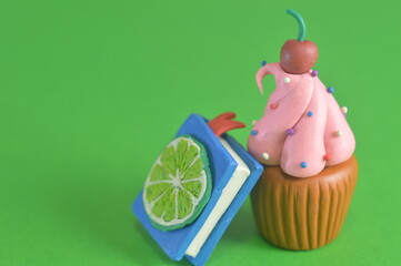 Plasticine cupcake and recipe book on green background