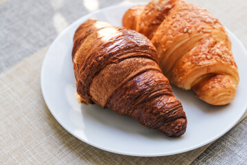 Fresh croissants close-up on a white breakfast plate.