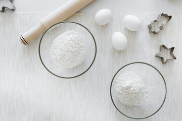white flour in a glass dish with eggs on the table