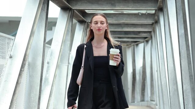 Portrait beautiful business woman walking go to working with coffee cup and using smartphone on city street