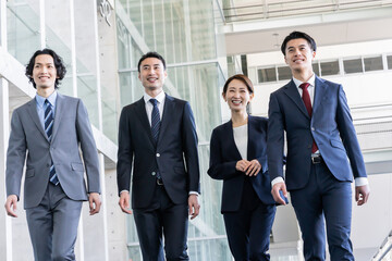 歩くスーツを着た日本人男女